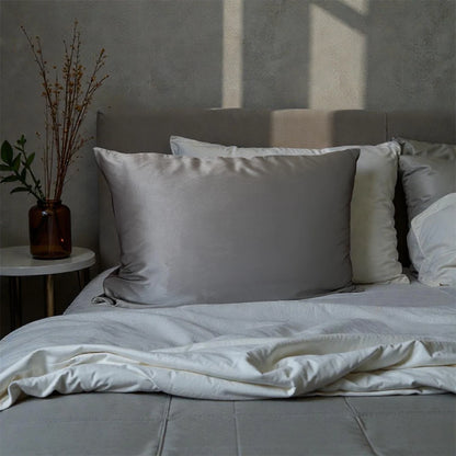 Bed with gray bedding and pillows in a softly lit room.